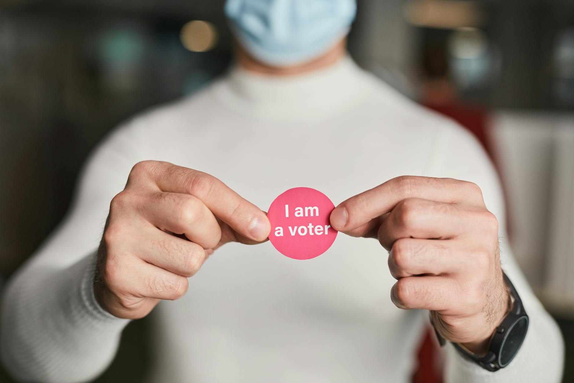 a person holding a voter pin