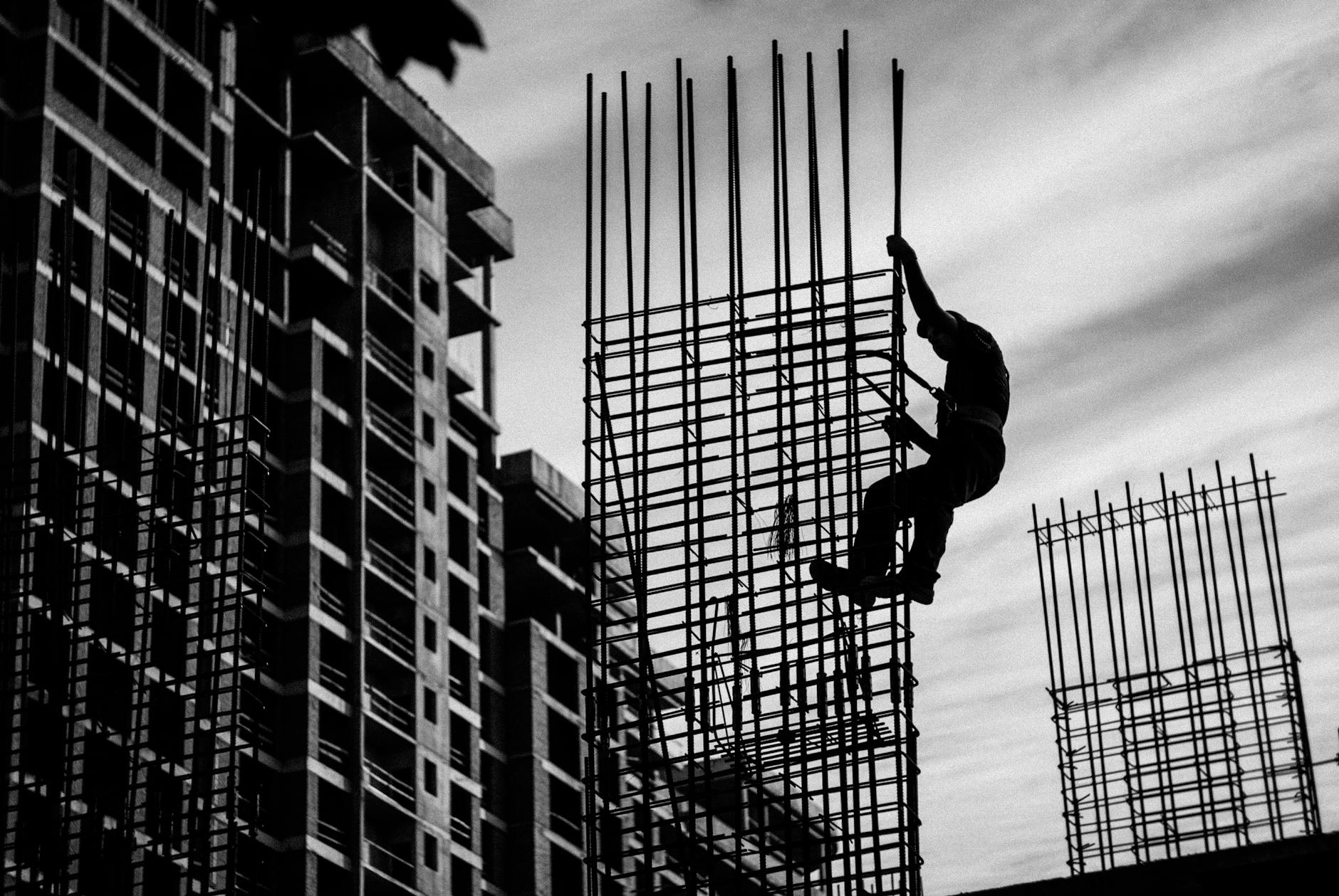 silhouette of man holding onto metal frame