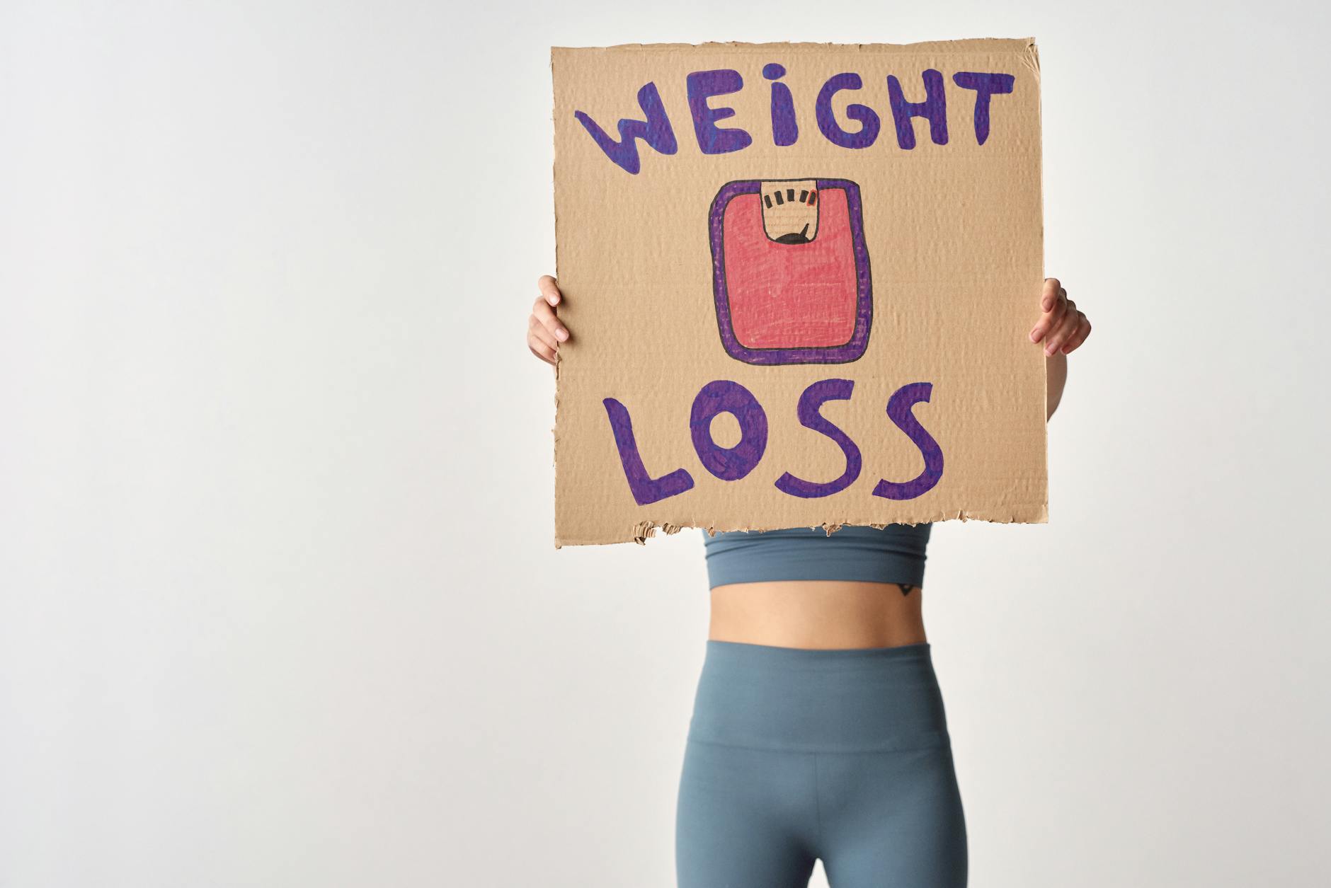 person holding a cardboard with weight loss message